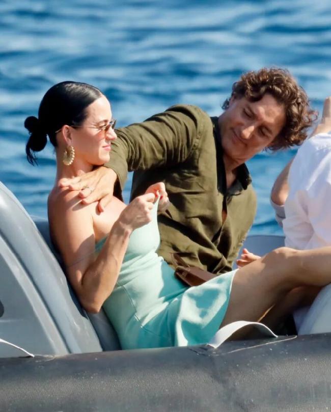 Katy Perry 转头看向右侧,特鲁多正在船上为她左肩涂防晒霜。